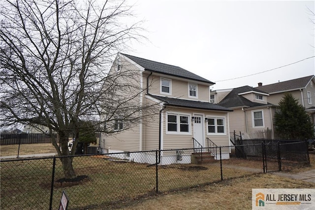 view of front of house featuring entry steps, fence private yard, a front lawn, and roof with shingles