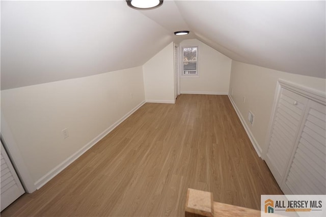 bonus room with vaulted ceiling, light wood-style floors, and baseboards