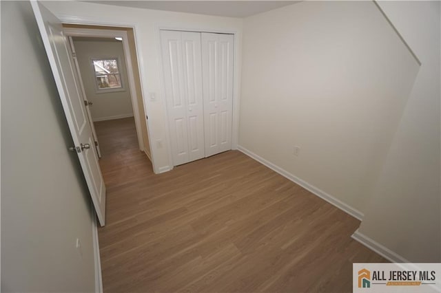 unfurnished bedroom with a closet, baseboards, and wood finished floors