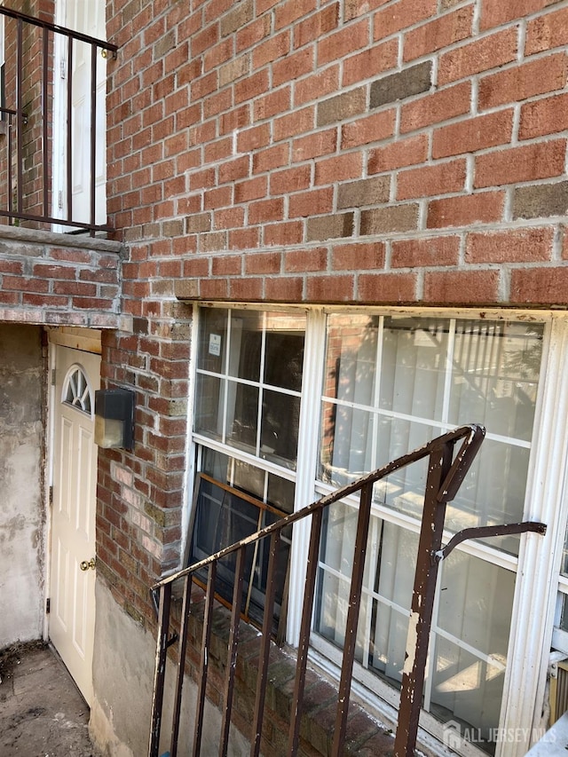 doorway to property featuring a garage and brick siding