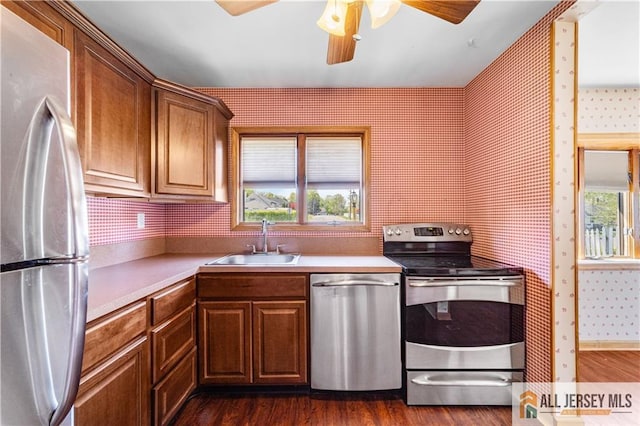 kitchen with stainless steel appliances, a sink, wallpapered walls, plenty of natural light, and a ceiling fan