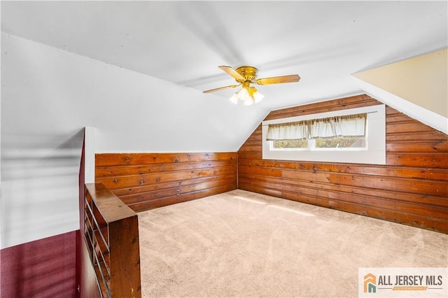 bonus room with wood walls, lofted ceiling, carpet flooring, and ceiling fan