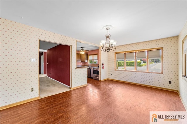 unfurnished living room featuring wallpapered walls, a chandelier, wood finished floors, baseboards, and ceiling fan