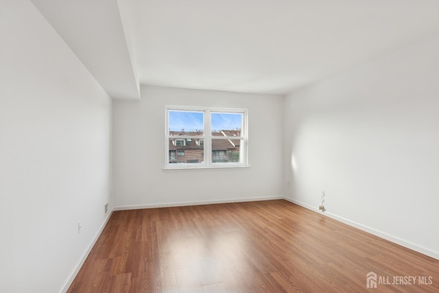 unfurnished room featuring baseboards and wood finished floors