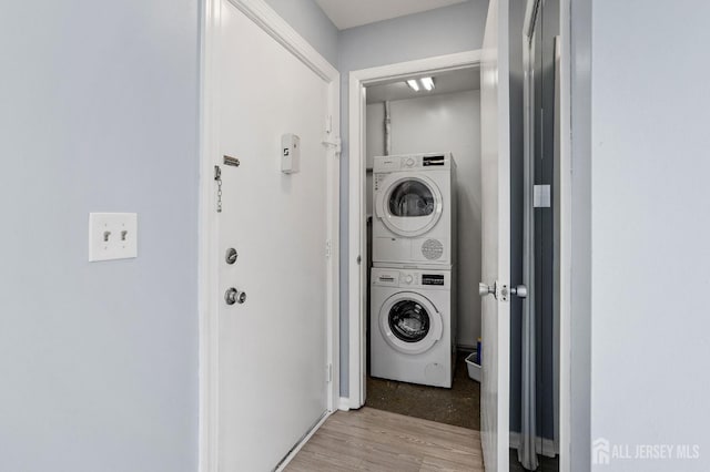 laundry area with light wood-type flooring and stacked washer / dryer