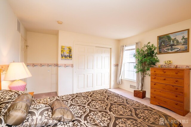 bedroom with light carpet and a closet