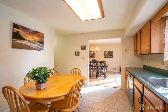 dining space with light tile patterned floors, a chandelier, and sink