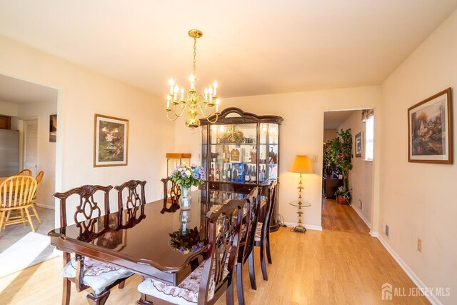 dining area with an inviting chandelier and light hardwood / wood-style floors