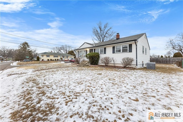 view of front of property featuring a chimney, fence, and central AC unit