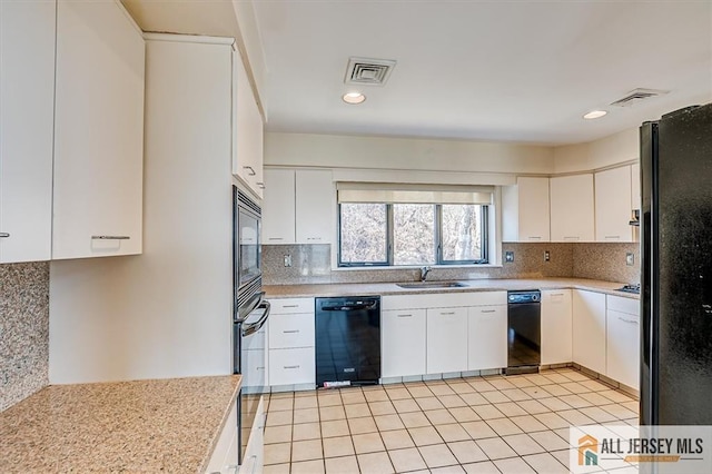 kitchen featuring visible vents, black appliances, a sink, tasteful backsplash, and light countertops