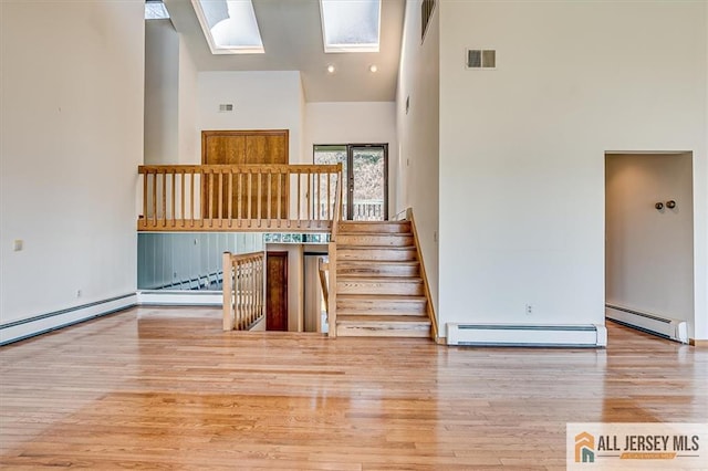 stairs featuring visible vents, high vaulted ceiling, a baseboard heating unit, wood finished floors, and baseboard heating