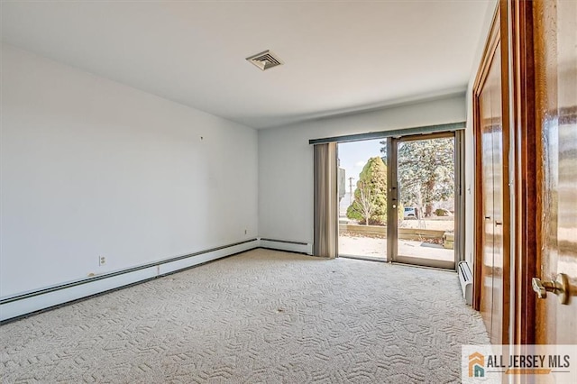 spare room with visible vents, baseboard heating, and carpet flooring