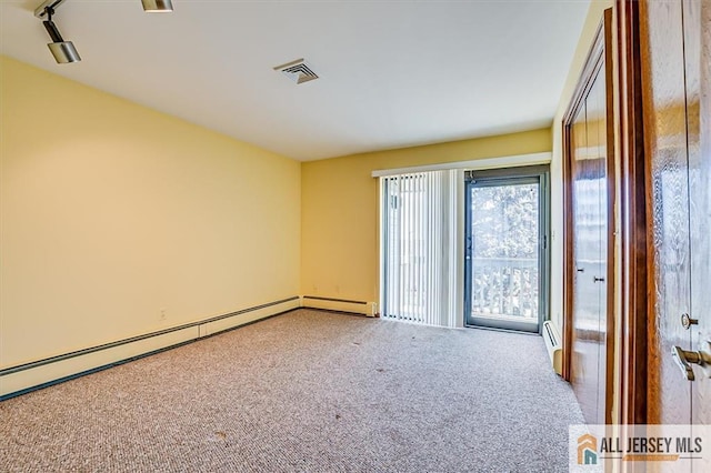 carpeted empty room featuring visible vents and a baseboard heating unit