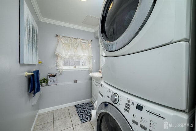 washroom featuring crown molding, baseboards, stacked washer and clothes dryer, cabinet space, and light tile patterned floors