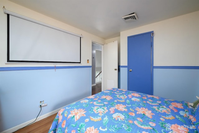 bedroom with baseboards, wood finished floors, visible vents, and a closet