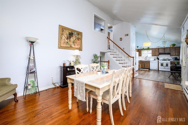 dining space with dark wood-style floors, high vaulted ceiling, and stairway