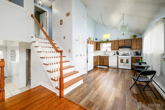 kitchen featuring an inviting chandelier, light countertops, visible vents, white appliances, and high vaulted ceiling