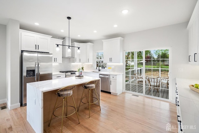 695 Inman Ave, Colonia, NJ 07067 - kitchen with appliances with stainless steel finishes, wall chimney range hood, tasteful backsplash, a kitchen bar, and white cabinets