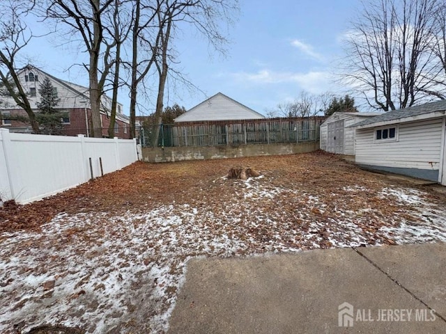 yard covered in snow with a storage unit, an outdoor structure, and a fenced backyard