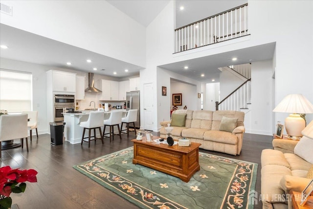 living room featuring dark wood-type flooring, sink, and a high ceiling