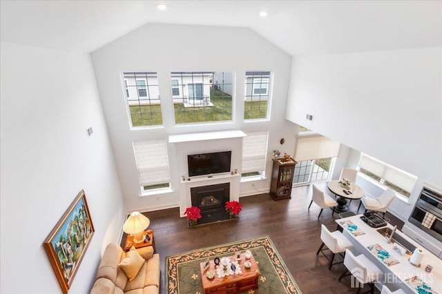 living room with a wealth of natural light, high vaulted ceiling, and dark hardwood / wood-style floors