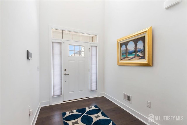 entryway with dark hardwood / wood-style floors and a towering ceiling