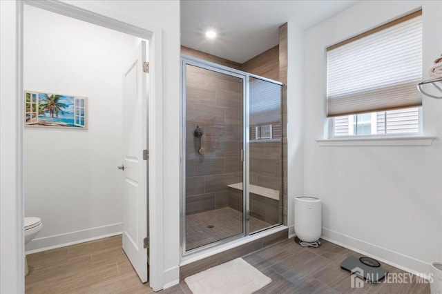 bathroom featuring hardwood / wood-style floors, a shower with door, and toilet