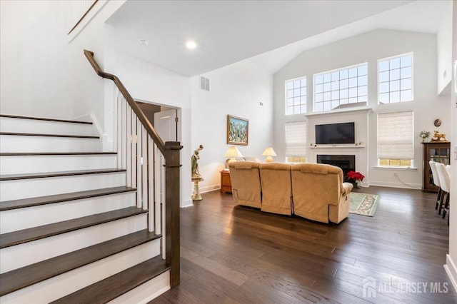 living room featuring dark wood-type flooring, high vaulted ceiling, and a wealth of natural light