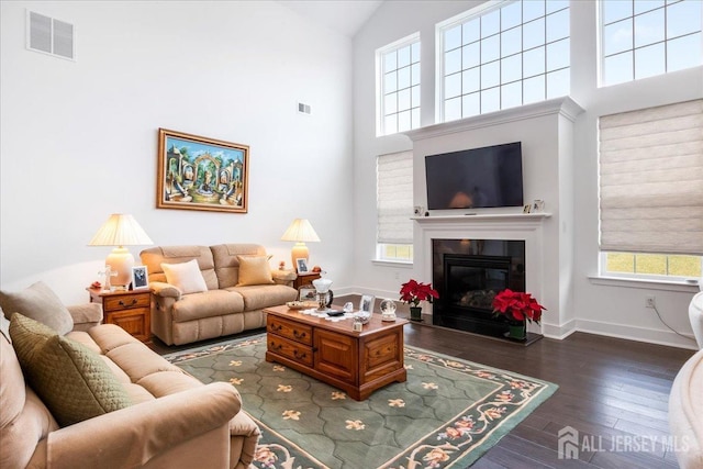 living room with dark hardwood / wood-style flooring and high vaulted ceiling