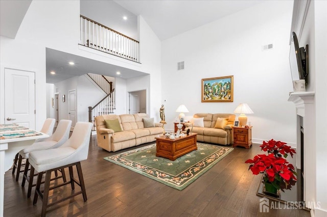 living room featuring a towering ceiling and dark hardwood / wood-style flooring