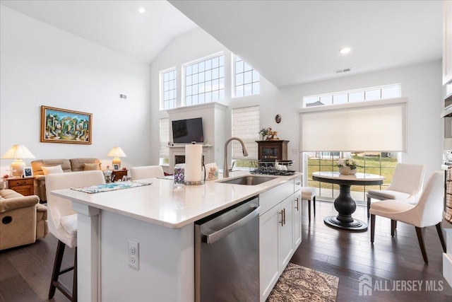 kitchen with white cabinetry, sink, stainless steel dishwasher, dark wood-type flooring, and a center island with sink