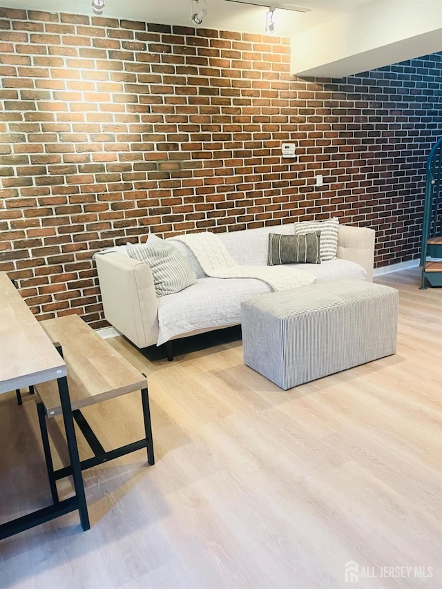 living room with light wood-type flooring and brick wall