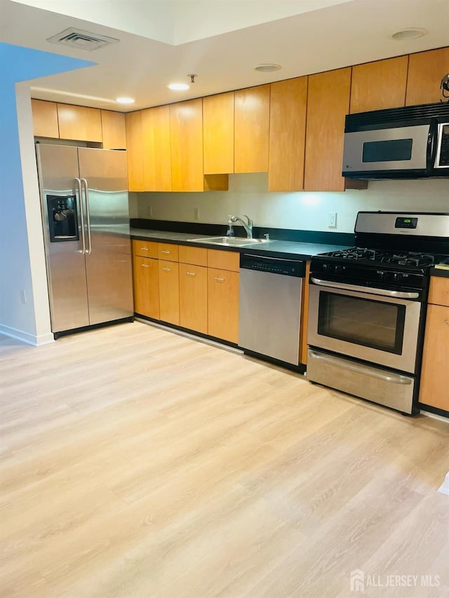 kitchen featuring light wood-type flooring, sink, and appliances with stainless steel finishes