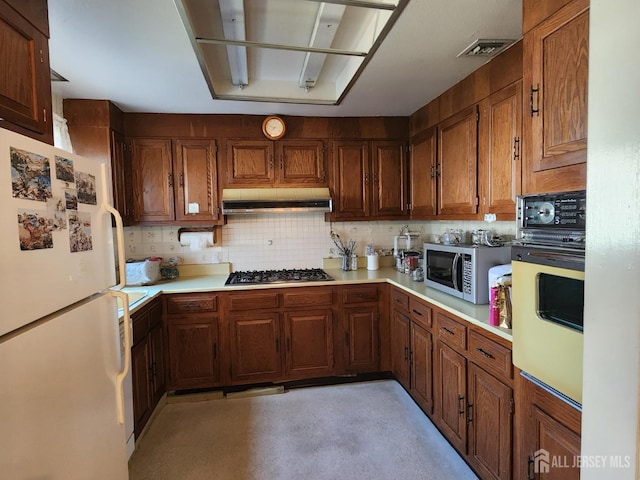 309-C Sharon Way, Monroe, NJ 08831 - kitchen with stainless steel appliances, under cabinet range hood, light countertops, backsplash, and brown cabinetry