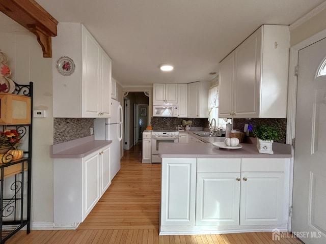 1515 Thomas Ave, North Brunswick, NJ 08902 - kitchen with white appliances, a sink, light wood finished floors, a peninsula, and white cabinetry
