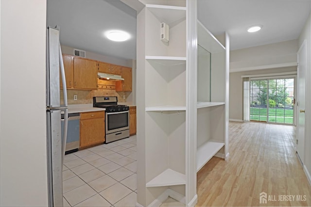 kitchen with stainless steel appliances, open shelves, under cabinet range hood, light countertops, and decorative backsplash