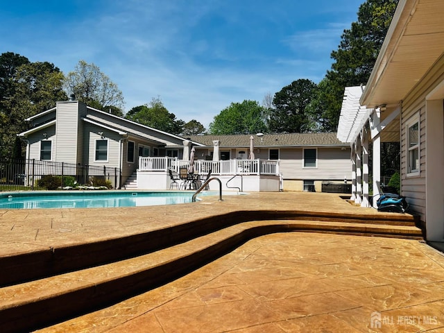 view of pool with a patio area, fence, a wooden deck, and a fenced in pool