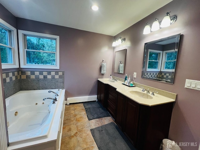 full bath featuring double vanity, plenty of natural light, baseboard heating, and a sink