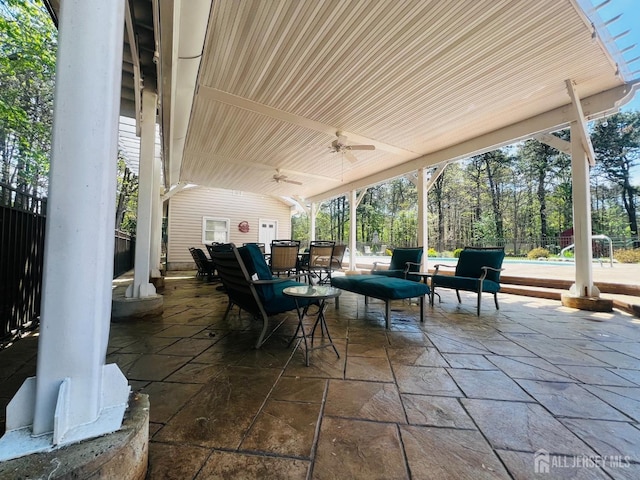 view of patio with outdoor dining area, ceiling fan, and fence