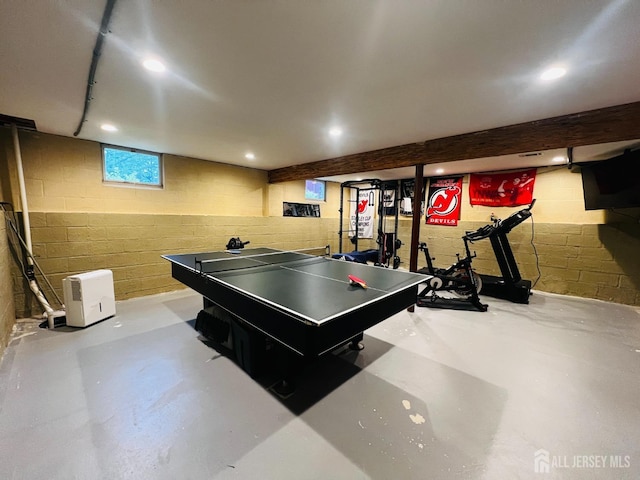 recreation room with finished concrete floors, concrete block wall, and recessed lighting