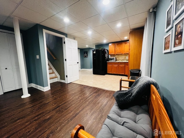 living area with wood finished floors, stairs, a paneled ceiling, baseboards, and recessed lighting