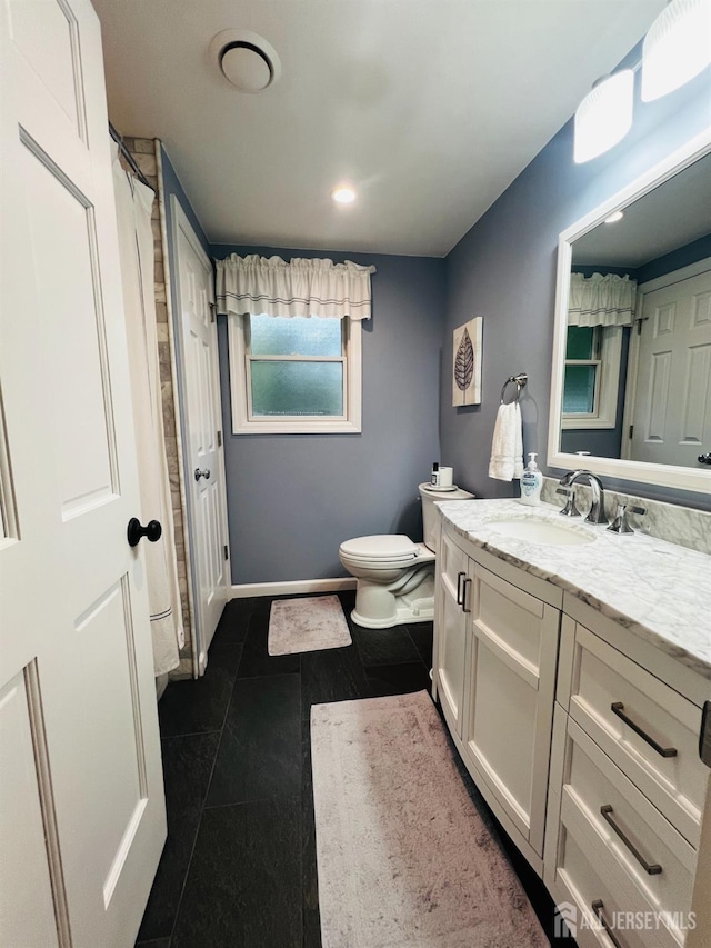 bathroom with vanity, toilet, baseboards, and tile patterned flooring