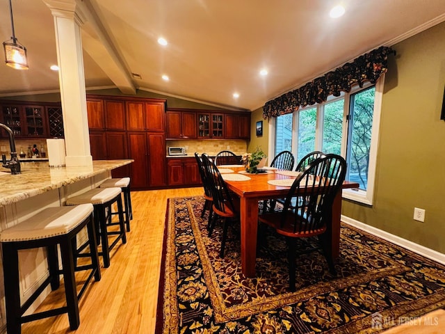 dining room with crown molding, lofted ceiling with beams, light wood-type flooring, and decorative columns