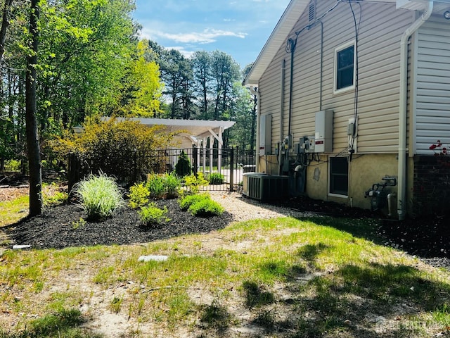 view of yard featuring central AC and fence