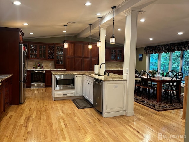 kitchen featuring beverage cooler, a sink, crown molding, vaulted ceiling, and stainless steel appliances