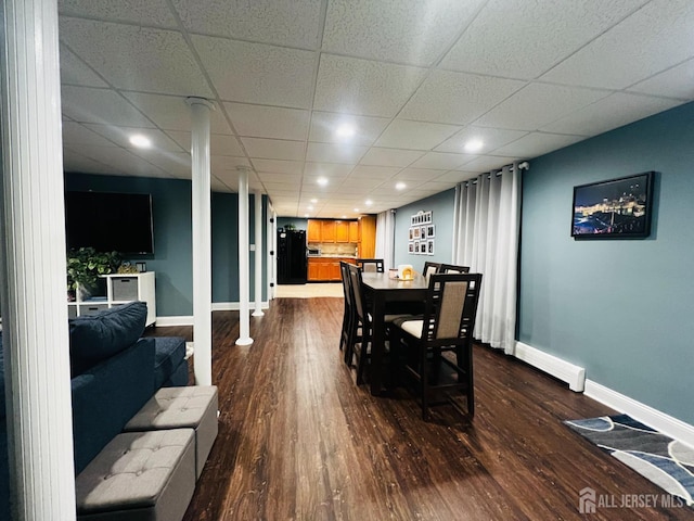 dining area featuring baseboards, a paneled ceiling, and dark wood-type flooring
