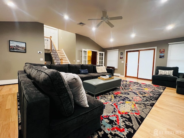 living area featuring stairs, visible vents, vaulted ceiling, ceiling fan, and light wood-style floors