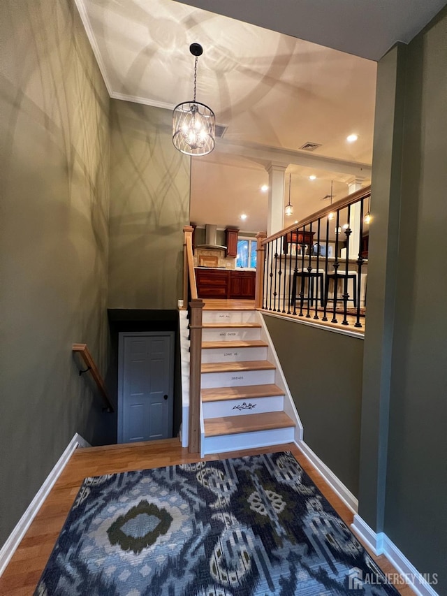 staircase featuring wood finished floors, ornamental molding, visible vents, recessed lighting, and a chandelier
