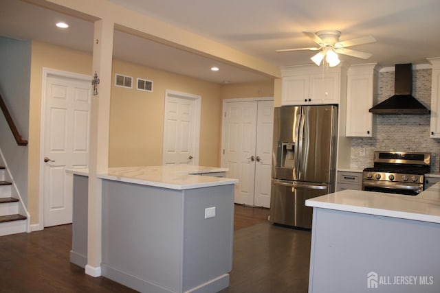 kitchen featuring wall chimney exhaust hood, tasteful backsplash, appliances with stainless steel finishes, ceiling fan, and white cabinets