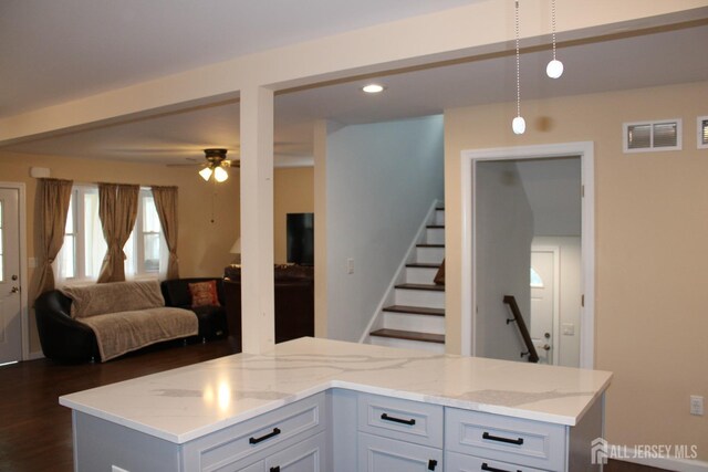 kitchen with light stone countertops, ceiling fan, pendant lighting, and white cabinetry